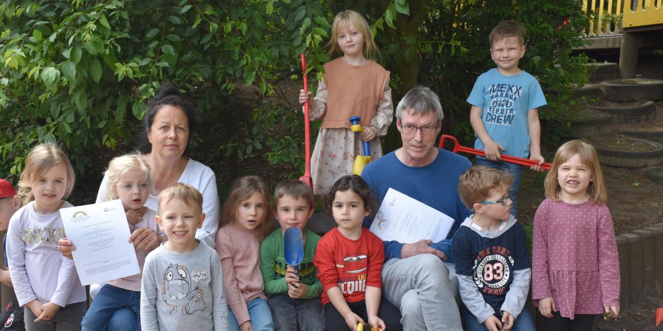 Birgit Hüsing-Hackfort (Familienzentrum), Dieter Homann (Caritas-Beratungsstelle) und Kinder aus dem Familienzentrum 'Zum Regenbogenland'.